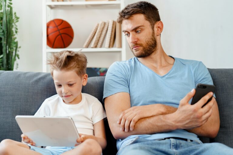 Worried father peeking at what his son is watching on digital tablet