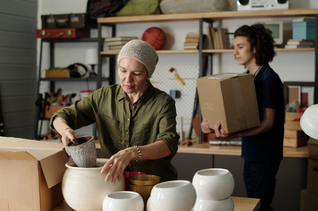 Female grandparent packing or unpacking boxes with various flowerpots