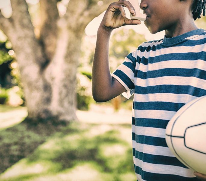 Boy using asthma inhaler in the park