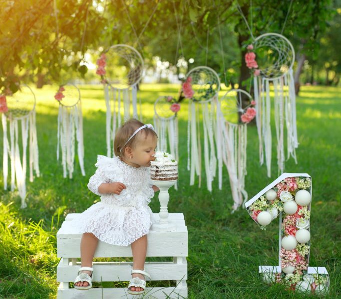 Girl bites a birthday cake in honor of the child's first birthday.