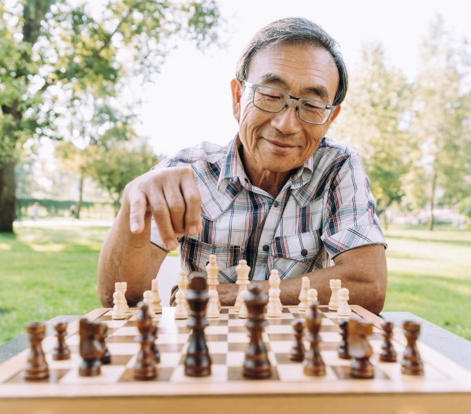 Group of senior friends playing chess at the park