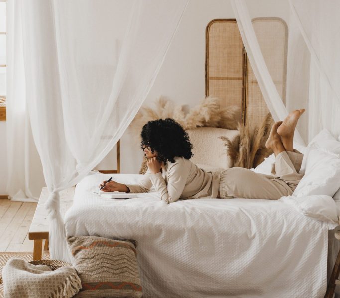 Young African American woman journaling in bed.